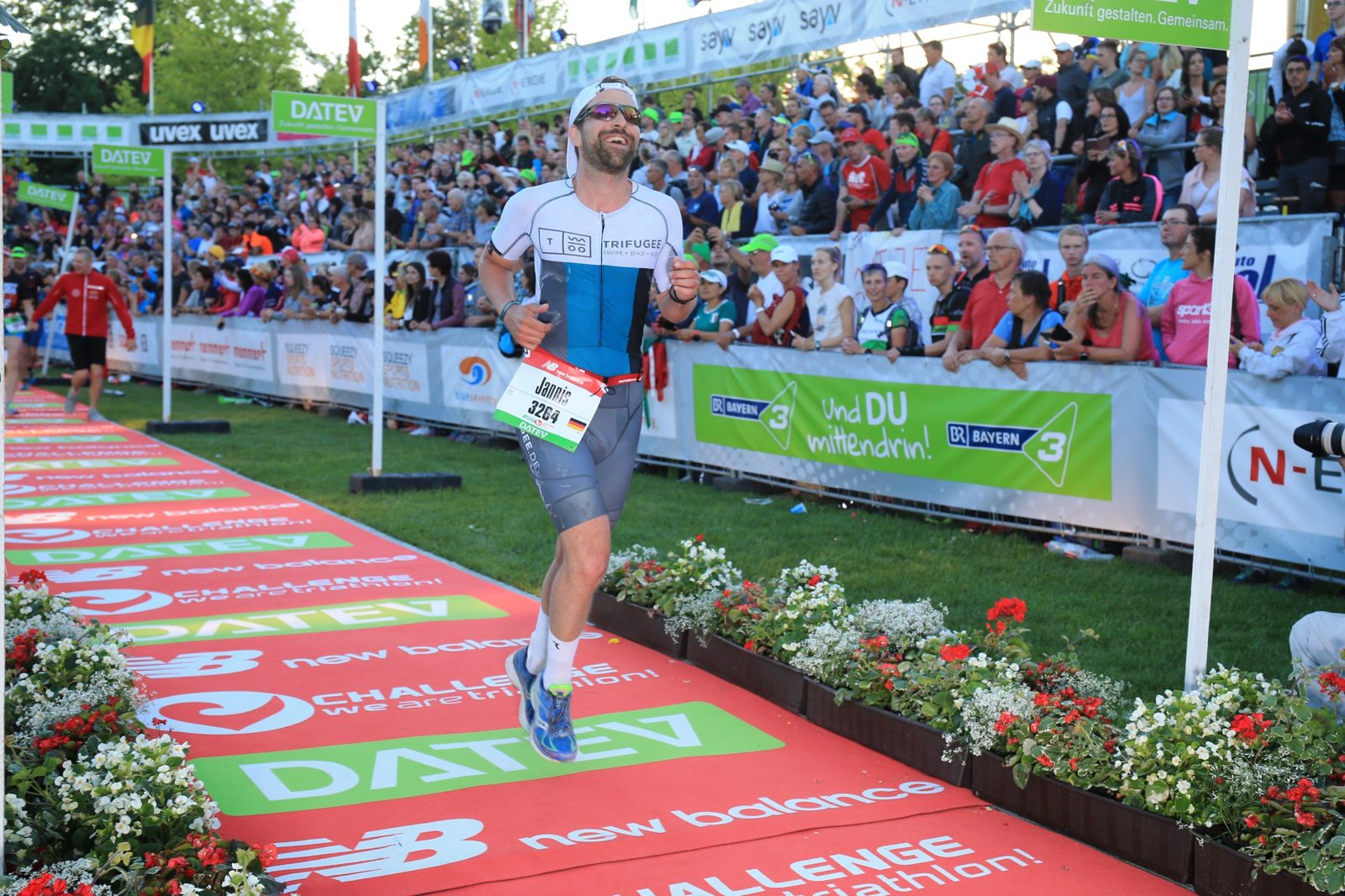 Jannis läuft lachend durch den Zielkanal der Challenge Roth, links und rechts volle Tribünen